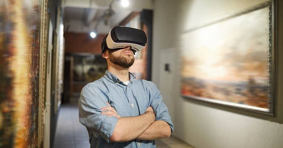 Man wearing a VR headset in a gallery surrounded by framed artworks